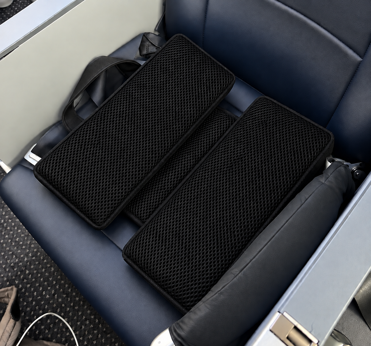 Black SunCloud® AirFlow travel seat cushion with full-surface cooling mesh shown on an airplane seat for cooler, more comfortable sitting.