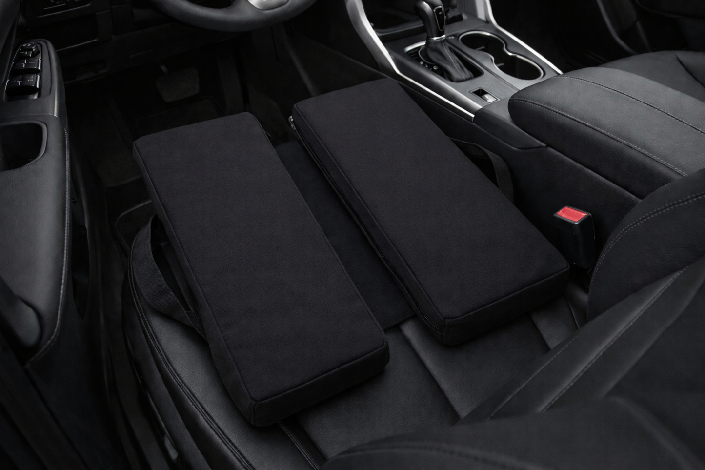 Black canvas SunCloud seat cushions placed on a car seat demonstrating ergonomic coccyx and pelvic support for travel and driving comfort.