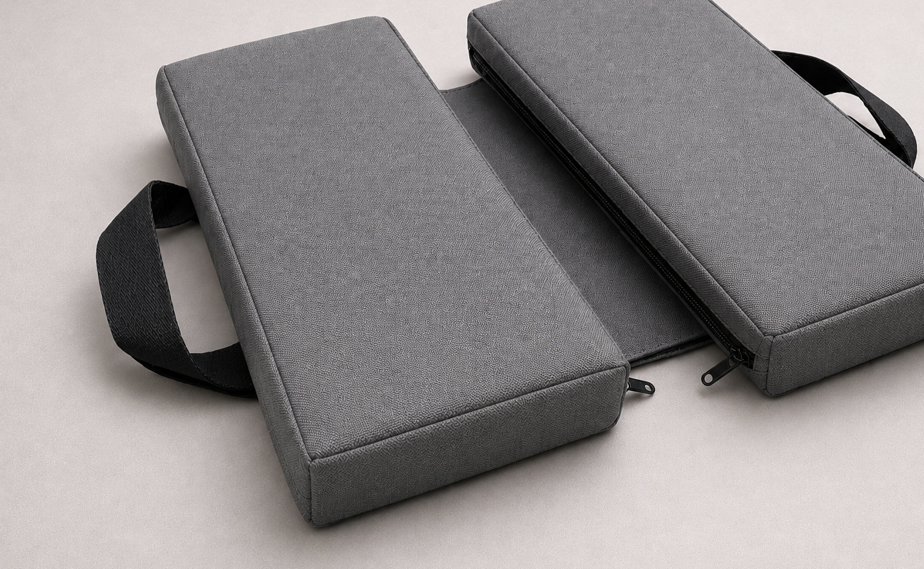 Gray foldable SunCloud® travel seat cushion with textured fabric, black zipper, and portable carrying handles on a light gray background.