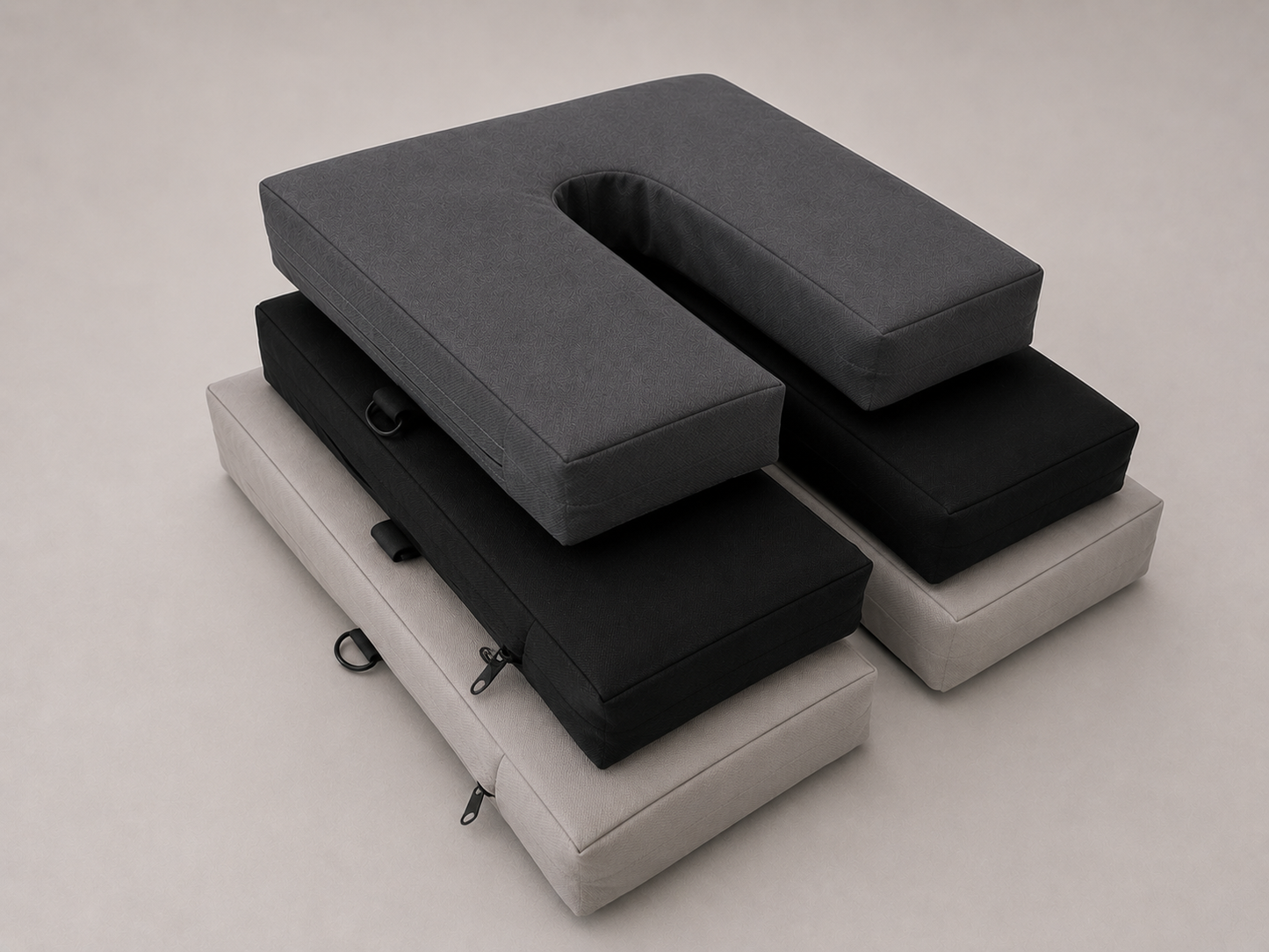 Stack of gray and black cushions on a beige surface